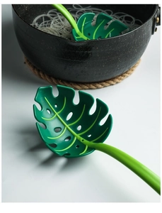 Macro detail of leaf-shaped green colander straining pasta from a black cooking pot