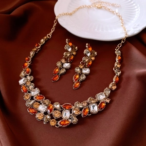 Macro shot of vintage style jewelry set with orange crystals on brown silk background