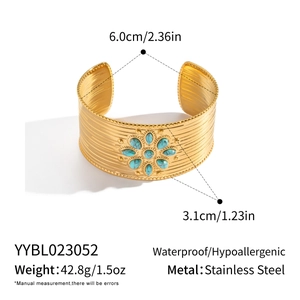 Detailed view of vintage gold-plated wide cuff bangle with turquoise stone floral inlay