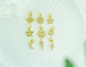 Close-up of nine 18K gold-plated brass charms with star and moon zircon inlays