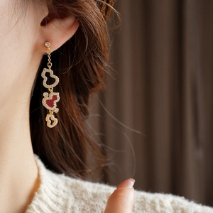 Macro shot of gold-plated gourd earrings featuring red inlay and sparkling zircon crystals