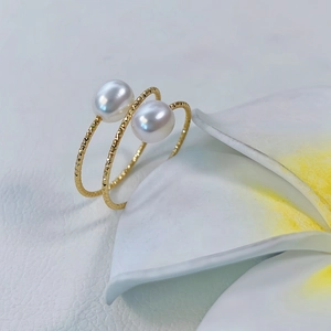 Macro detail of gold spiral pearl ring with hammer-textured finish on frangipani flower