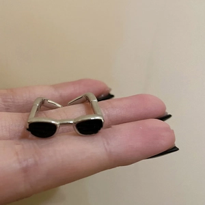 Vue macro d'une bague y2k en forme de lunettes de soleil argentées et émail noir