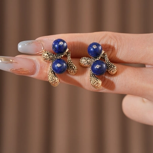 Macro detail of vintage gold flower stud earrings with dark blue beads and crystals