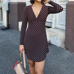 Detailed close-up of a V-neck polka dot mini dress featuring long sleeves and waist tie