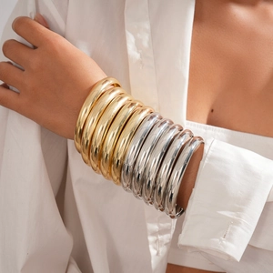 Macro shot of stacked chunky gold and silver metallic bangles on a wrist