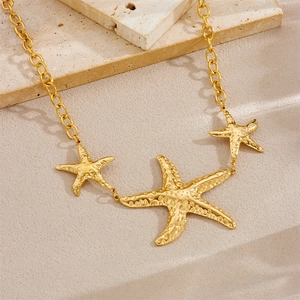 Exaggerated golden starfish pendant necklace on stone background with O-chain texture