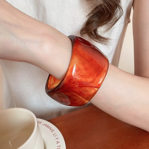 Close-up of amber resin cuff bracelet with tortoiseshell pattern on woman wrist