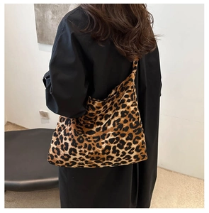 Detail of a large leopard print tote bag styled with a minimalist black dress for commuting