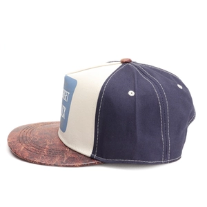 Detail of a color-block baseball cap featuring blue, beige, and brown faux leather brim