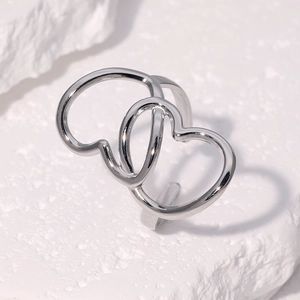 Détail d'une bague ouverte à double cœur entrelacé en argent sur surface en pierre