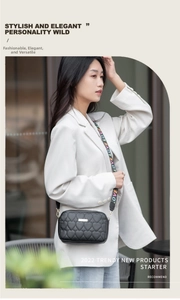 Detail of black heart-quilted crossbody bag with colorful LOVE letter woven strap