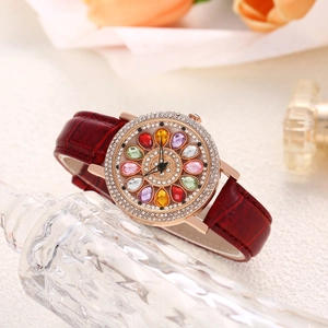 Detail of luxury women's watch featuring a crystal bezel and floral gemstone dial design