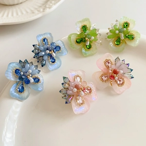 Détail de boucles d'oreilles fleurs avec pétales en résine bleu vert et rose