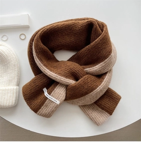 Detail of chunky knit scarf in brown and beige color block with stitched woven label