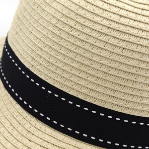 Detailed close-up of straw hat weaving texture and black ribbon with white stitching