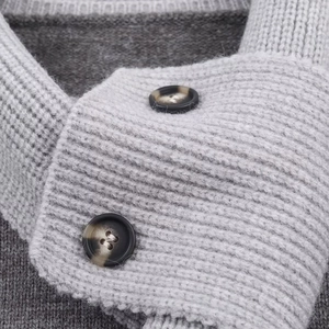 Détail du col en maille grise avec boutons ronds vintage et texture en laine douce
