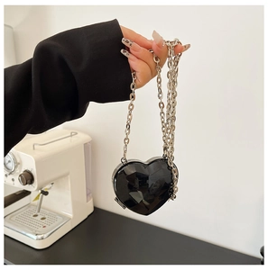 Macro view of a black heart-shaped acrylic evening bag with a silver chain strap