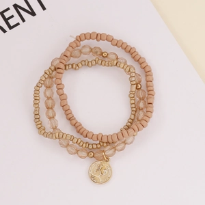 Detail of multi-layer beaded bracelet with nude pink beads and gold coin pendant