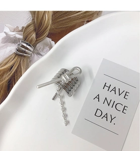 Macro detail of silver metal hair hook with layered spiral design and pearl chain fringe