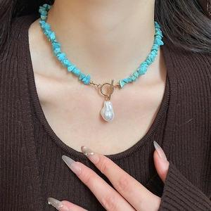 Detail of bohemian turquoise beaded necklace with baroque pearl and golden toggle clasp