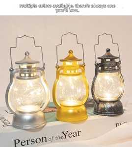 Vintage LED lantern ornaments in silver, gold, and black on a book for Christmas decor