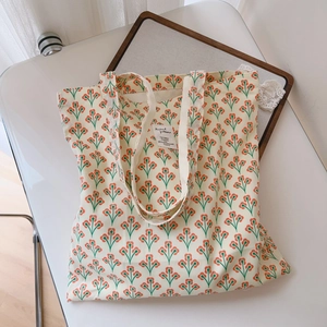 Close-up of vintage orange floral canvas tote bag with a woven label on white background
