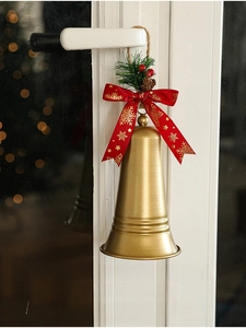 Detail of Christmas bell with red bow and pine cone hanging on a white door handle