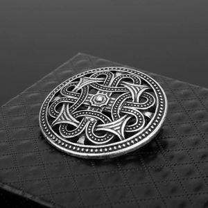 Macro view of vintage Viking silver shield brooch with intricate Celtic knot engraving