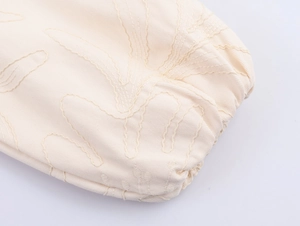 Detailed macro view of beige twill cotton fabric with intricate floral embroidery stitching