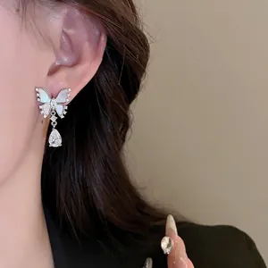 Asymmetric butterfly earrings with mother of pearl and teardrop zircon on a model