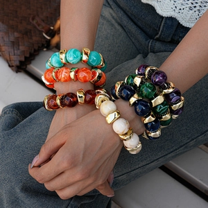 Detailed view of layered bohemian acrylic beaded bracelets with gold spacer beads on wrist