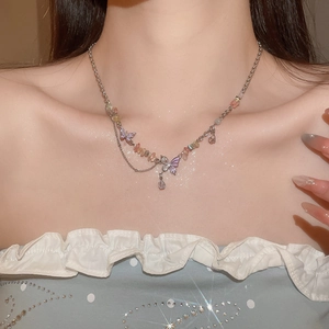 Detail of silver chain necklace with pink butterfly pendants and colorful gravel beads