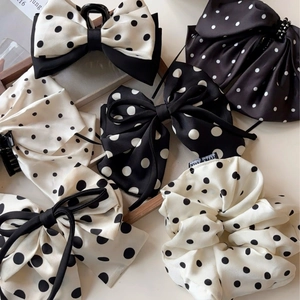 Set of black and white polka dot silk scrunchies and bow clips on a wooden tray