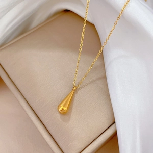 Detailed macro view of a gold waterdrop pendant necklace on white silk background