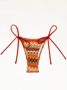 Detail of red side-tie bikini bottom featuring bohemian zigzag geometric knit patterns