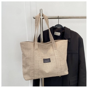 Detail of beige canvas tote bag showing heavy woven texture and sturdy shoulder handle