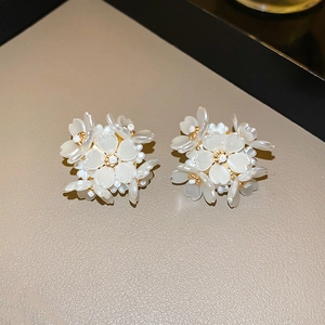 Macro detail of elegant flower stud earrings with white resin petals and gold stamen