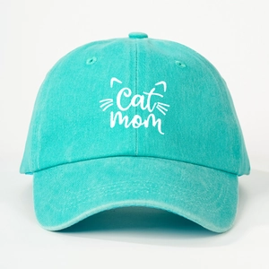 Close-up of turquoise cotton baseball cap featuring white Cat Mom embroidery and cat ears