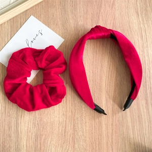 Red velvet scrunchie and knotted headband set displayed on a wooden surface