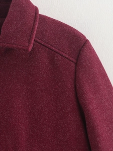 Detaillierte Makroansicht des weinroten Tweed-Stoffs und der sauberen Nähte der Jacke