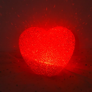 Red heart-shaped LED prop light with textured finish on a star-patterned mesh background