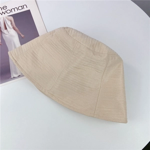 Détail d'un chapeau bob beige avec texture plissée sur fond blanc épuré