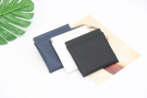 Three-color faux leather storage pouches in blue, white, and black with metal snap closure