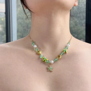 Detail showing the green beads, golden starfish and shell charms on the summer necklace