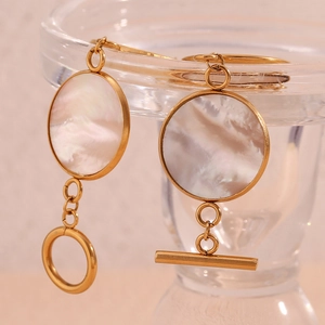 Macro detail of round white mother-of-pearl earrings with 18K gold-plated OT toggle closure