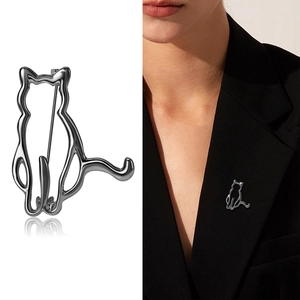Minimalist silver cat-shaped brooch in hollow outline style shown on suit and white background
