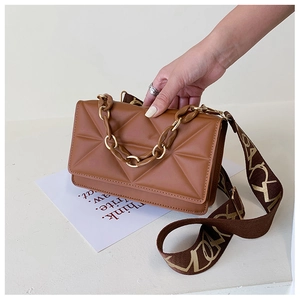 Close-up of caramel brown leather handbag featuring geometric quilting and metal chain strap