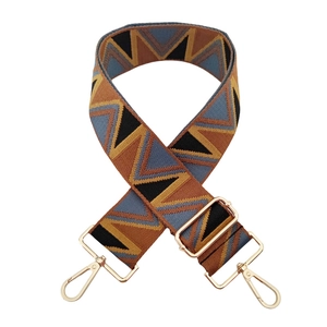 Close-up of jacquard woven geometric strap with golden metal swivel snap hooks