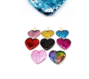 Close-up of vibrant reversible sequin heart keychains with golden metal lobster clasps